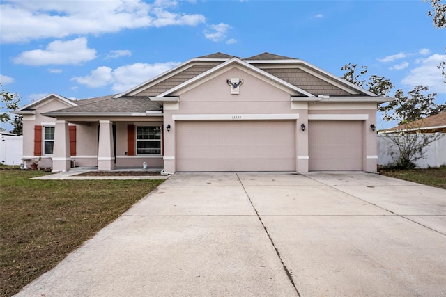 view of front of house with covered porch, a garage, and a front lawn