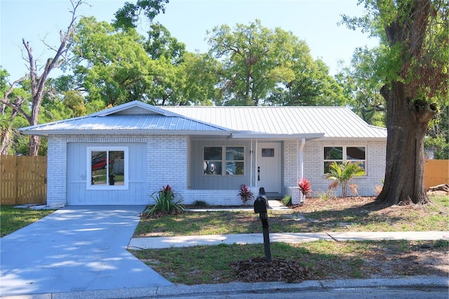 single story home with fence, brick siding, and metal roof