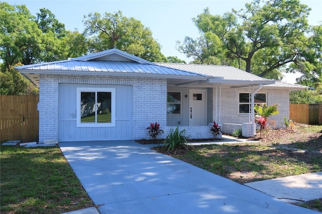 ranch-style home featuring metal roof, brick siding, covered porch, and fence