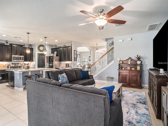 tiled living room with ceiling fan and a textured ceiling