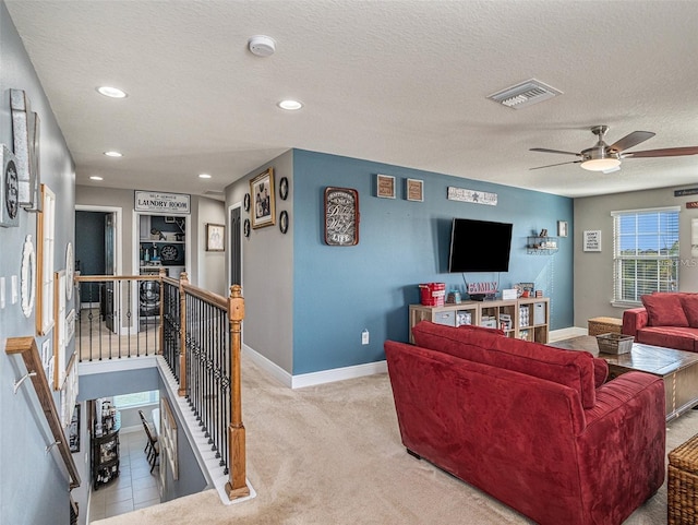 carpeted living room with ceiling fan and a textured ceiling