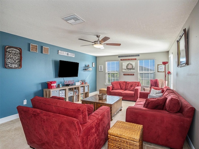 living room with a textured ceiling, light colored carpet, and ceiling fan