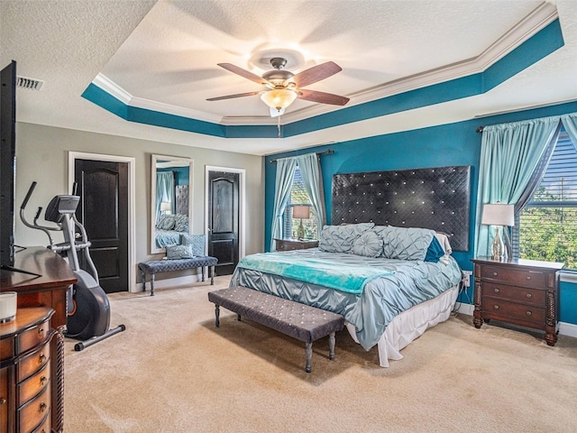 bedroom with light colored carpet, multiple windows, a tray ceiling, and ceiling fan