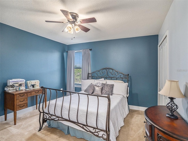 bedroom featuring ceiling fan, light colored carpet, a textured ceiling, and a closet