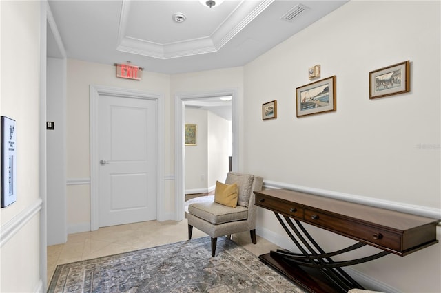 sitting room with a raised ceiling and ornamental molding