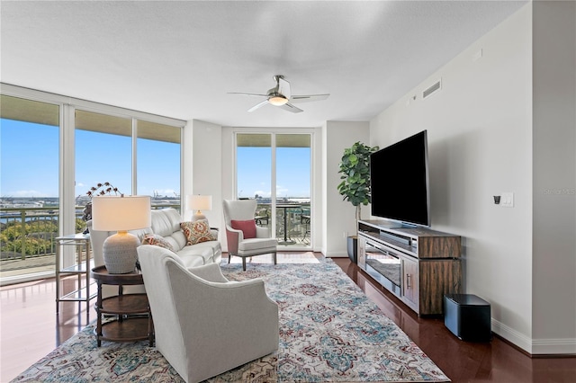 living room featuring ceiling fan, expansive windows, and dark wood-type flooring