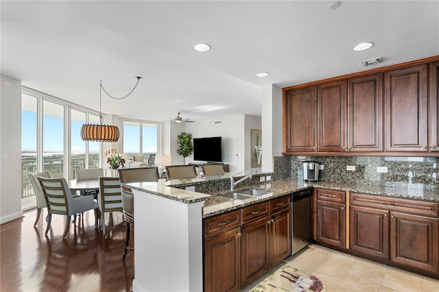 kitchen with kitchen peninsula, ceiling fan, sink, dishwasher, and hanging light fixtures