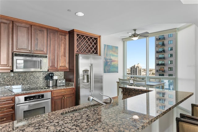 kitchen with a breakfast bar, sink, dark stone countertops, appliances with stainless steel finishes, and tasteful backsplash