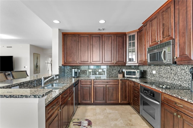 kitchen with sink, stainless steel appliances, tasteful backsplash, kitchen peninsula, and dark stone countertops