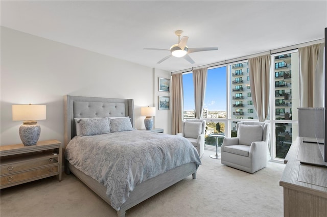 carpeted bedroom featuring expansive windows and ceiling fan