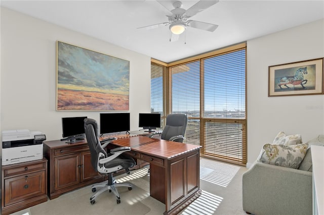 carpeted office space featuring ceiling fan