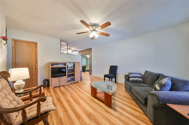 living room featuring ceiling fan, light hardwood / wood-style floors, and a textured ceiling