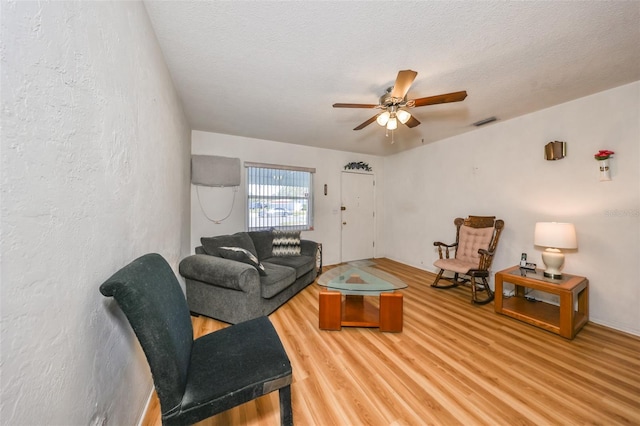 living room with ceiling fan, hardwood / wood-style floors, and a textured ceiling