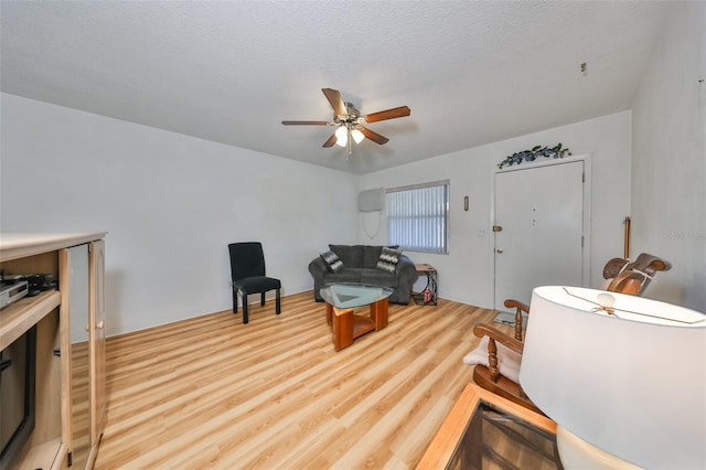 living room featuring a textured ceiling, light hardwood / wood-style floors, and ceiling fan