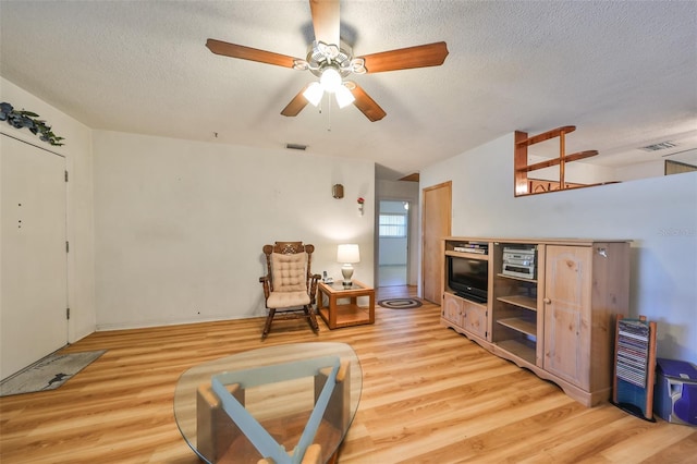 living area featuring a textured ceiling, light wood-type flooring, and ceiling fan