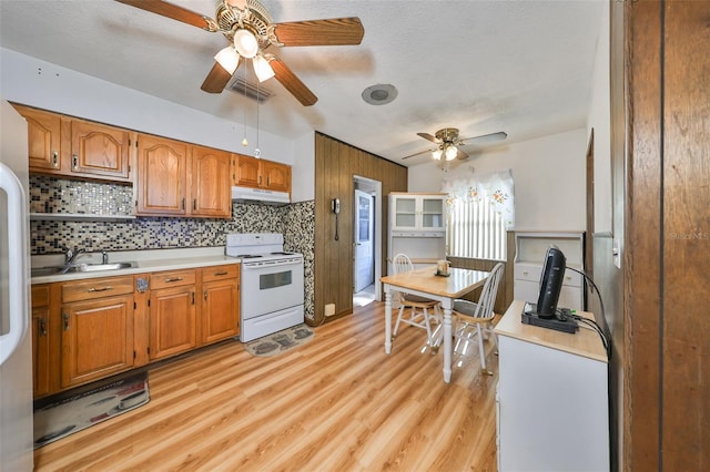 kitchen with electric stove, sink, decorative backsplash, a textured ceiling, and light hardwood / wood-style floors