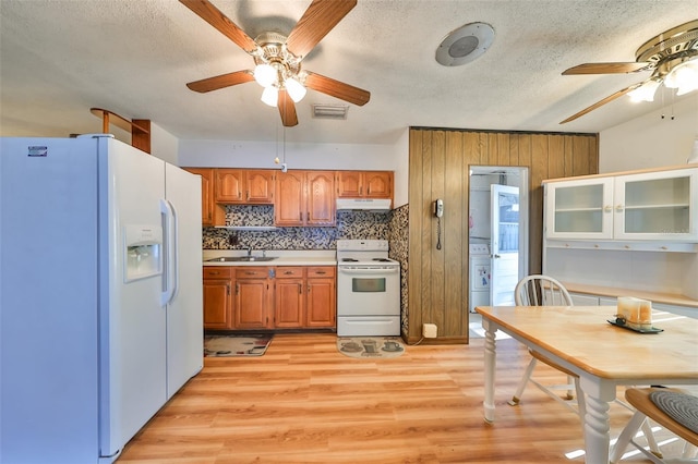 kitchen featuring decorative backsplash, a textured ceiling, white appliances, sink, and light hardwood / wood-style floors