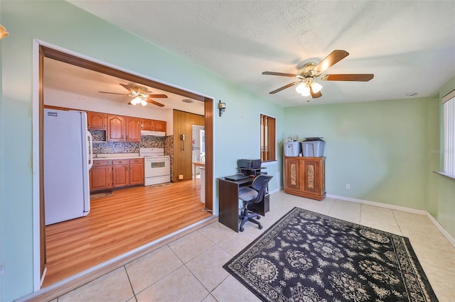 kitchen featuring a textured ceiling, white appliances, light hardwood / wood-style floors, and backsplash