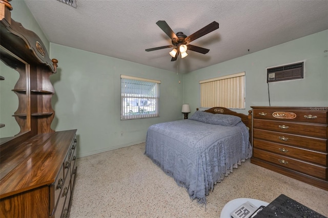 bedroom with a wall mounted AC, ceiling fan, and a textured ceiling