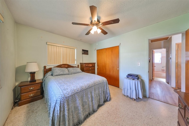 bedroom featuring ceiling fan, ensuite bathroom, a textured ceiling, and a closet