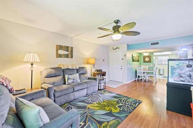 living room featuring wood-type flooring, a textured ceiling, and ceiling fan