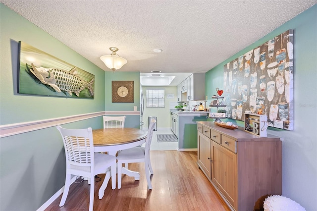 dining area featuring a textured ceiling, light hardwood / wood-style flooring, and sink