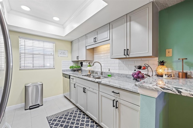 kitchen with backsplash, light stone counters, crown molding, and sink