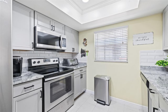 kitchen with decorative backsplash, light stone countertops, stainless steel appliances, and light tile patterned floors