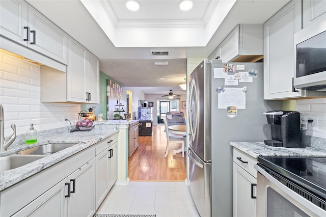 kitchen featuring white cabinets, stainless steel appliances, light stone counters, and ceiling fan