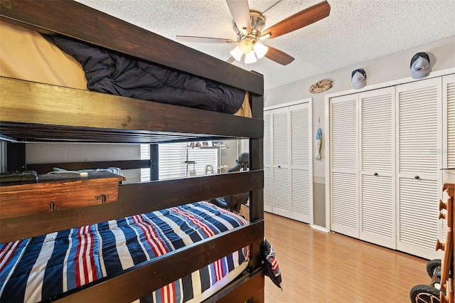 bedroom featuring multiple closets, ceiling fan, light hardwood / wood-style flooring, and a textured ceiling