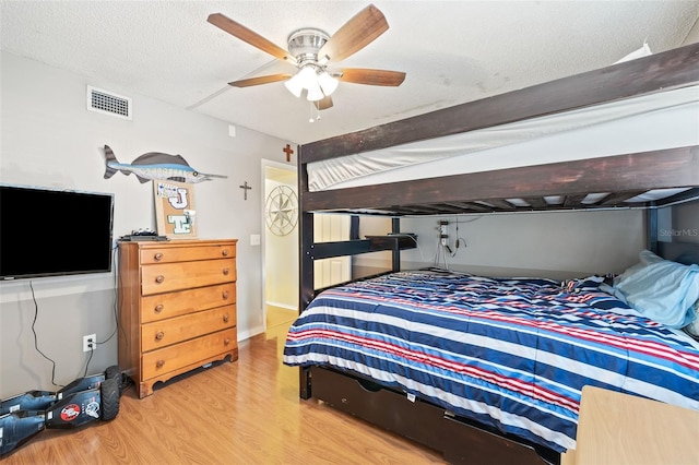 bedroom featuring beamed ceiling, ceiling fan, a textured ceiling, and light hardwood / wood-style flooring