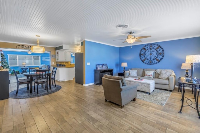 living room featuring ceiling fan, ornamental molding, and light wood-type flooring