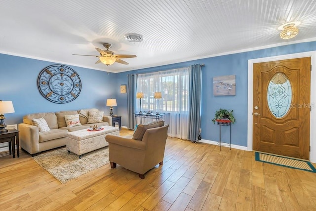 living room with light hardwood / wood-style floors, ceiling fan, and ornamental molding