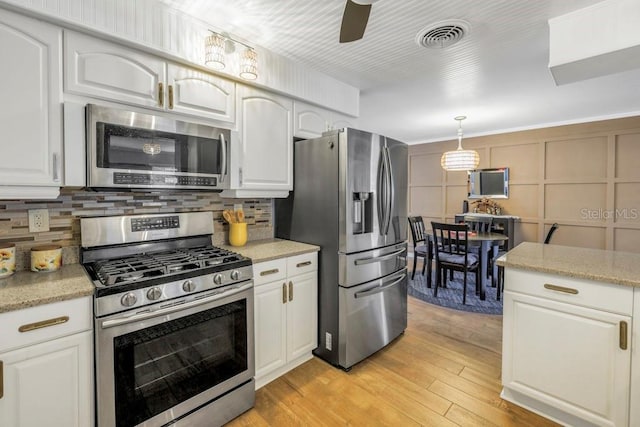 kitchen featuring pendant lighting, backsplash, white cabinetry, light hardwood / wood-style floors, and stainless steel appliances