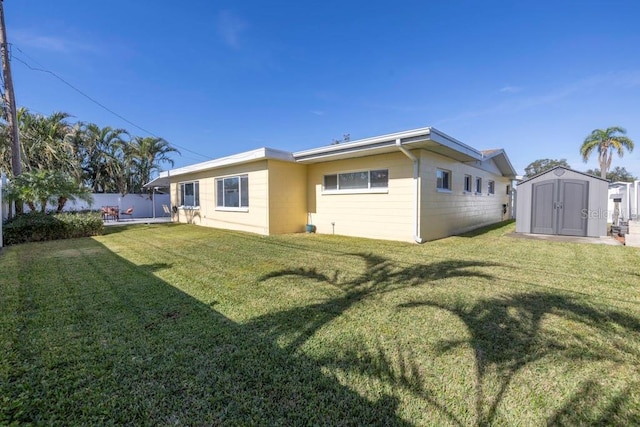 rear view of property with a yard and a storage unit