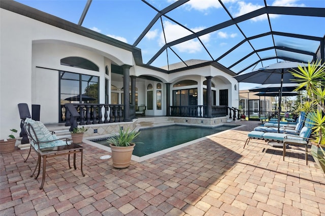 view of pool featuring glass enclosure, ceiling fan, and a patio area