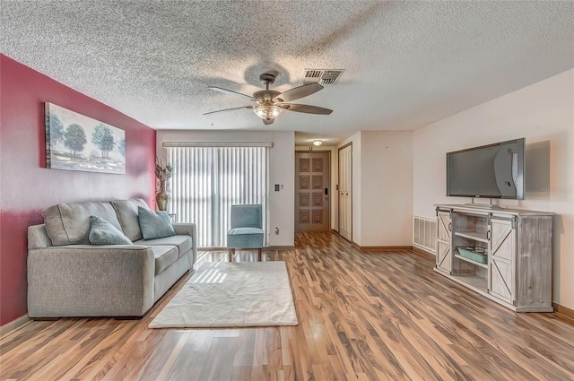 living room with ceiling fan, a textured ceiling, and hardwood / wood-style flooring