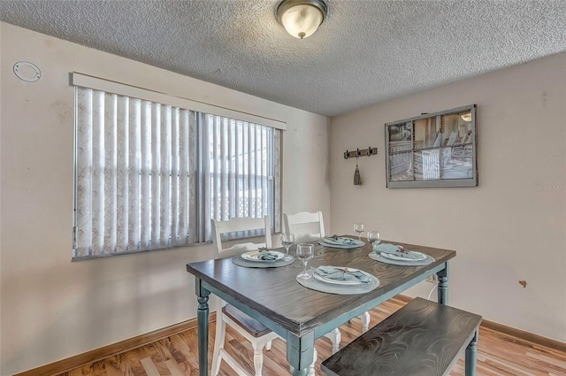 dining space with light hardwood / wood-style flooring and a textured ceiling