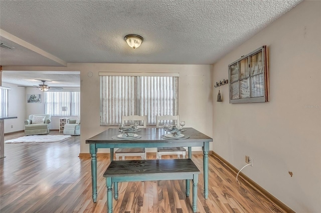 dining room featuring ceiling fan, wood-type flooring, and a textured ceiling