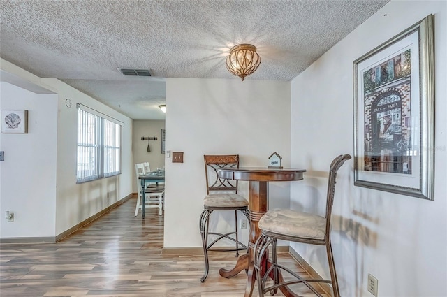 dining area with wood-type flooring and a textured ceiling