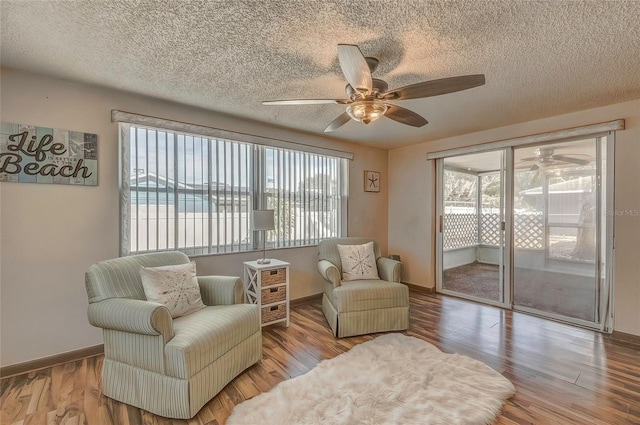 sitting room featuring a water view, light wood-type flooring, and a textured ceiling