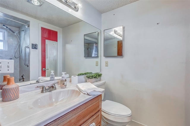 bathroom featuring toilet, a tile shower, a textured ceiling, and vanity