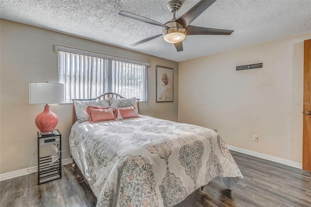 bedroom with a textured ceiling, ceiling fan, and dark wood-type flooring