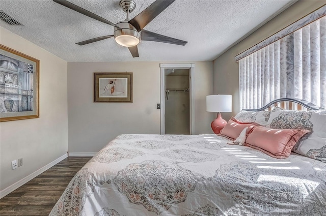 bedroom with ceiling fan, dark hardwood / wood-style floors, a spacious closet, and a textured ceiling