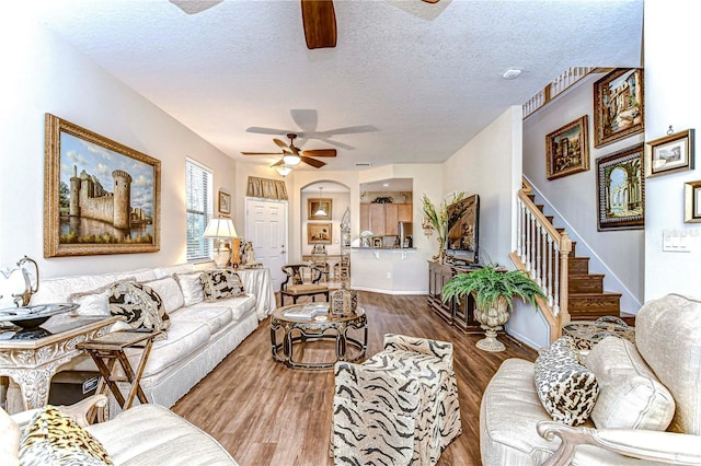 living room featuring hardwood / wood-style flooring, ceiling fan, and a textured ceiling