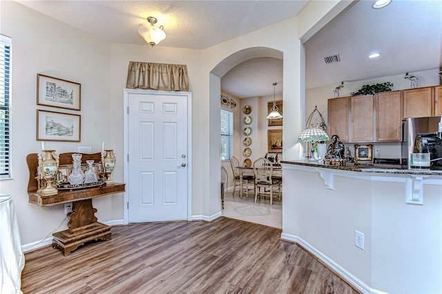 entrance foyer with a textured ceiling and light hardwood / wood-style floors