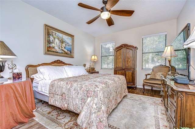 bedroom with multiple windows, light hardwood / wood-style flooring, and ceiling fan