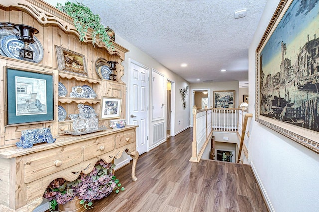 hall with hardwood / wood-style flooring and a textured ceiling