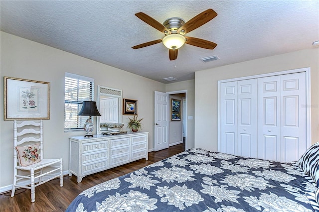 bedroom with a textured ceiling, ceiling fan, dark wood-type flooring, and a closet