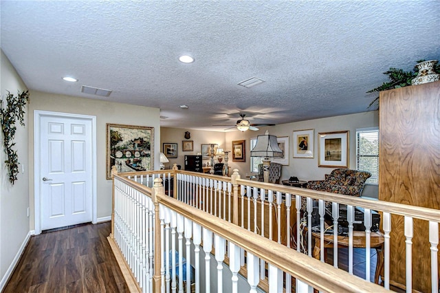 hallway with a textured ceiling and dark hardwood / wood-style floors